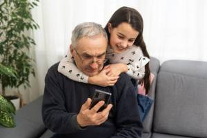 Old man with granddaughter look at phone together