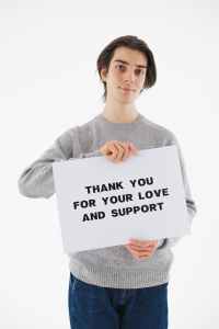 Young man holds sign reading Thank You for your Love and Support