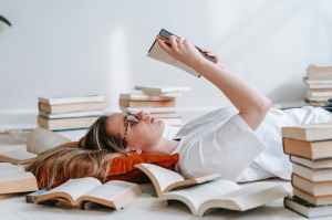 A woman laying down among books reading