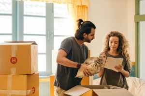 A couple looks at a checklist while packing boxes inside a house