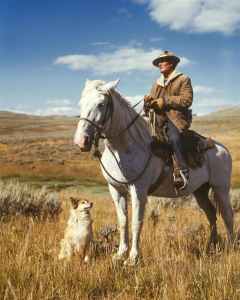 Man on a horse with dog on the ground next to him